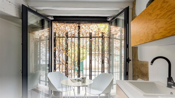 Un baño moderno con puerta de vidrio, lavamanos blanco y grifo negro.