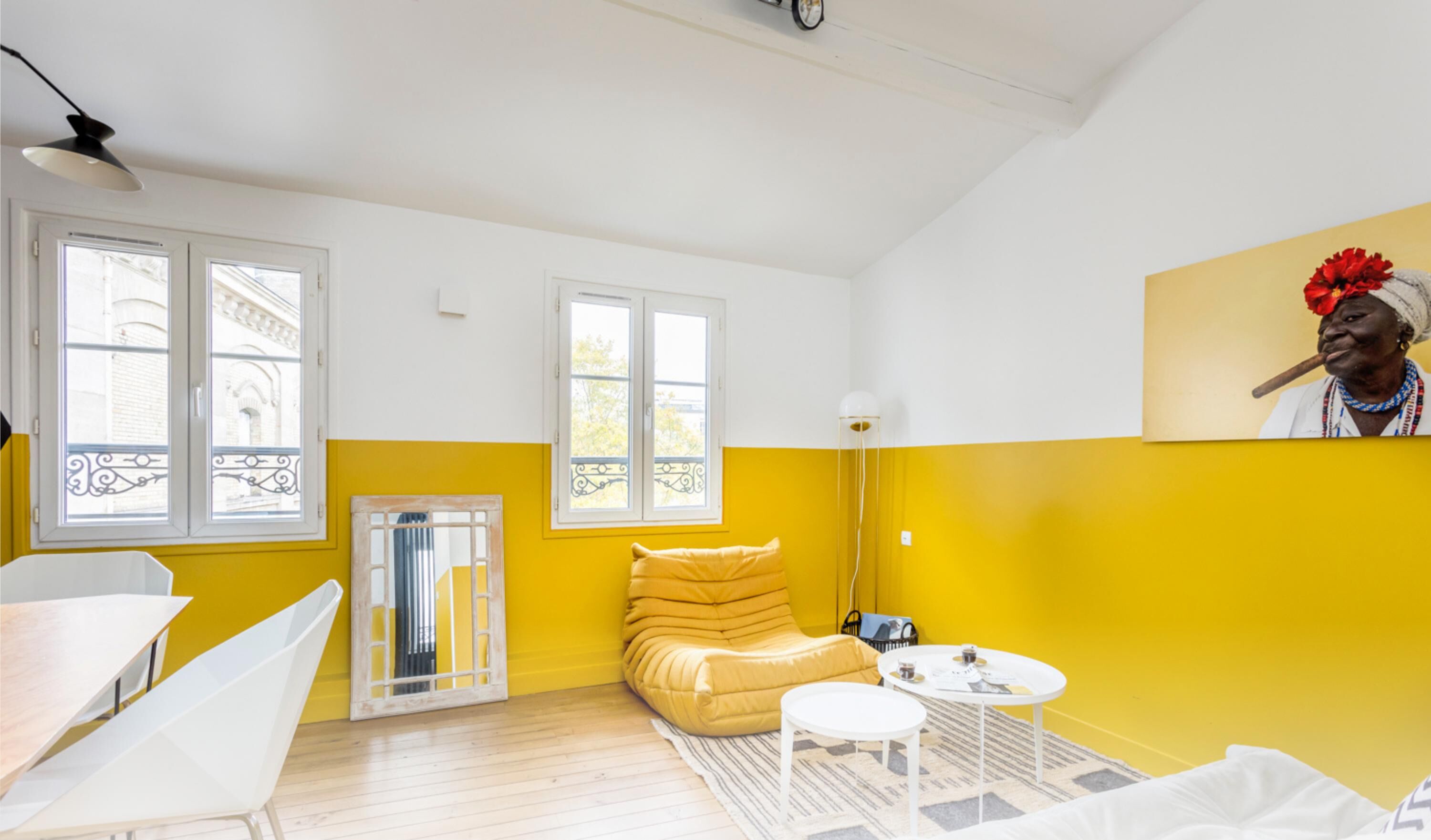 Een kamer met een geel-wit kleurenschema, met een bank, een ronde tafel en een stoel.