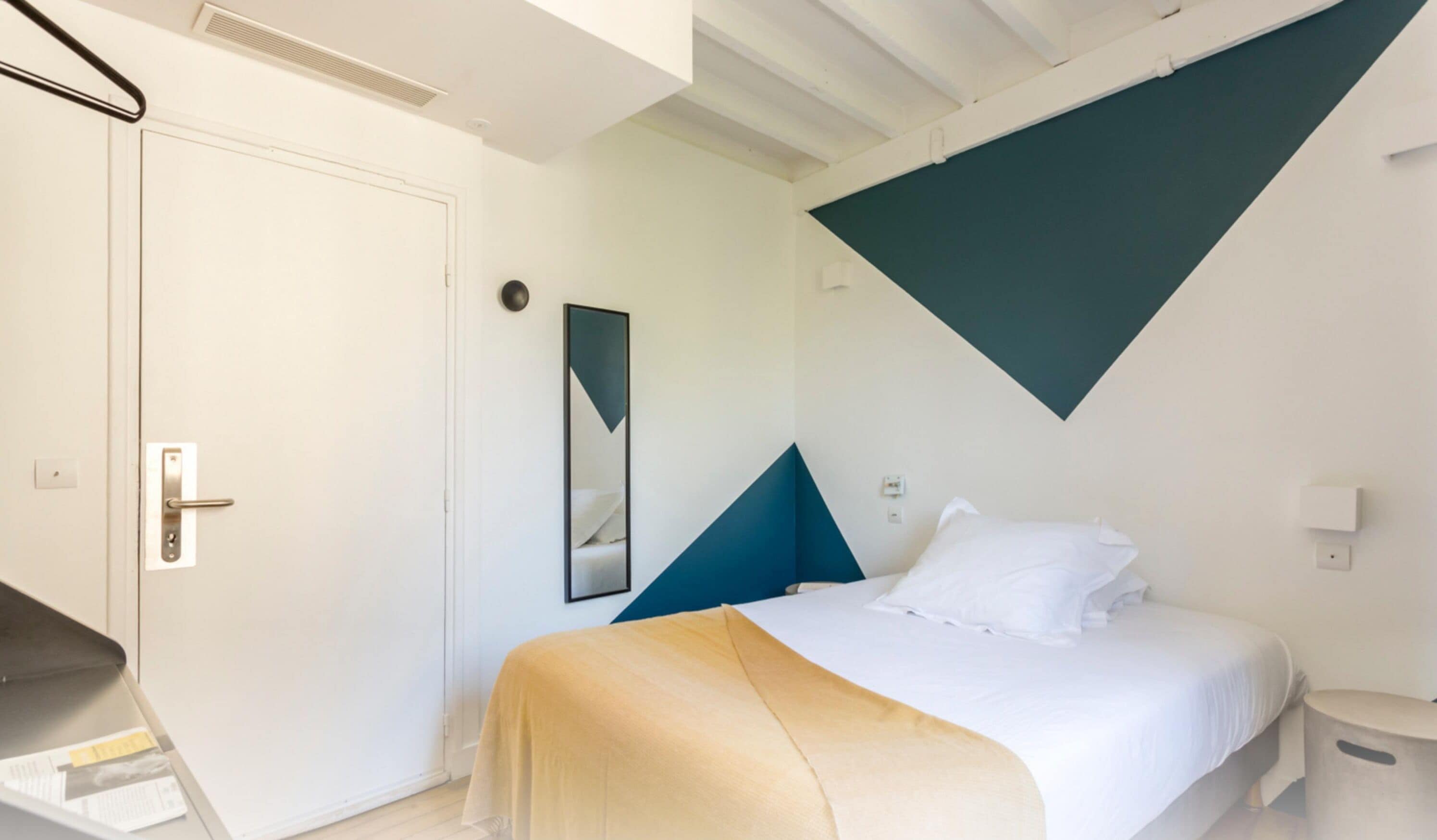 A modern bedroom with a bed, a bedside table, a chair, and a door.