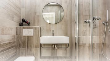 A modern bathroom with a white sink, a round mirror, and a glass shower enclosure.