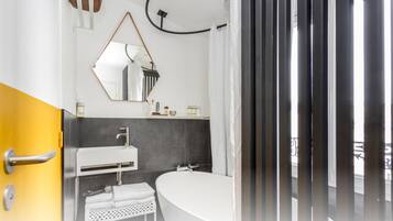 A modern bathroom with a white sink, a large mirror, and a bathtub.