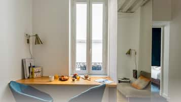 A modern room with a wooden desk, a chair, a bed, and a window with a view of a balcony.
