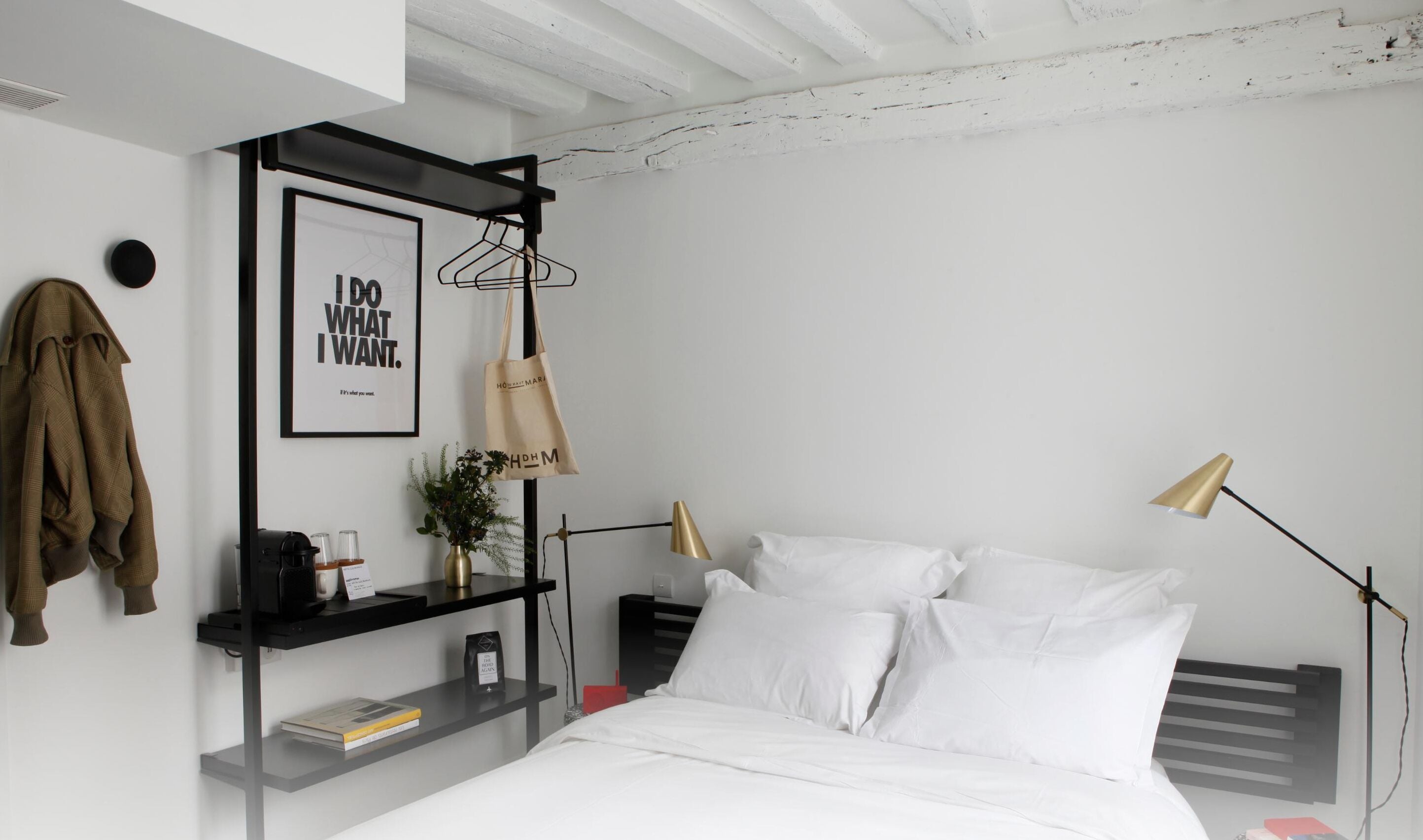 A modern bedroom with a bed, bedside tables, a hanging light, a wall-mounted shelf, and a motivational poster.