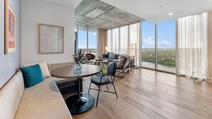 A modern living room with a round dining table, a sofa, and a view of the city through large windows. - Sunshine Condo in Downtown Austin (Austin)