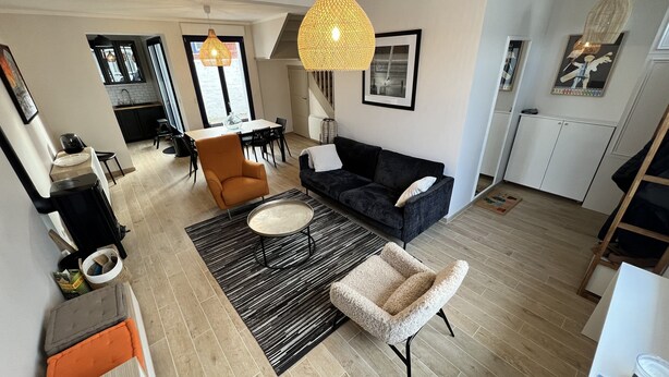 A modern living space with a dining area, a sofa, a coffee table, and a kitchen in the background.