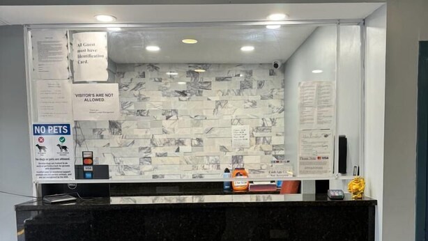 A reception area with a black marble counter, a 'NO PETS' sign, and a 'VISITOR'S ARE NOT ALLOWED' sign. - Midtown Lodge (Jacksonville)