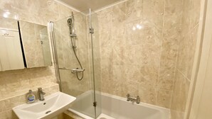 Une salle de bain avec une douche à parois de verre, un lavabo et une baignoire.