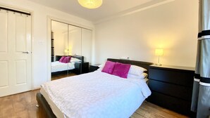 Une chambre à coucher avec un lit, des tables de chevet, un miroir et un luminaire suspendu.