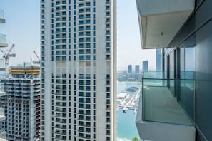 Un edificio de gran altura con varios balcones que dan a un puerto deportivo y al paisaje urbano.