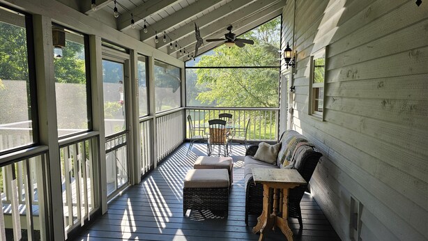 Een overdekte veranda met een houten bank, een tafel en stoelen.