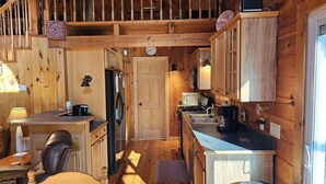 Een compacte keuken met houten kastjes, een koelkast, een fornuis en een gootsteen.