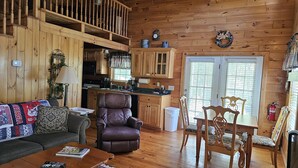 A cozy cabin interior with a living room, a dining area, and a kitchen. - Magnolia-Cabin sits on Coosa creek with a breath taking view of the falls (Blairsville)
