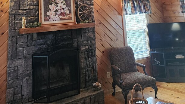 A cozy cabin interior with a stone fireplace, wooden ceiling, and a comfortable seating area. - Magnolia-Cabin sits on Coosa creek with a breath taking view of the falls (Blairsville)