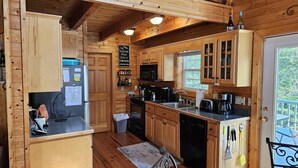 A wooden cabin kitchen with wooden cabinets, a refrigerator, a sink, and a coffee maker. - *FAMILY GETAWAY*Deck/Firepit/HOT TUB & Fireplace (Blairsville)