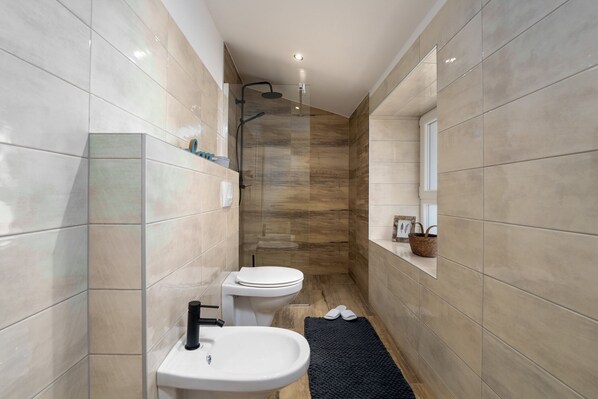 A modern bathroom with a white sink, toilet, and shower area.
