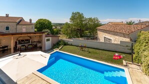 A swimming pool with a clear blue water, surrounded by a wooden deck and a covered seating area. - Villa Corinna (Istria - Poreč) (Poreč)