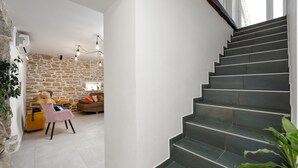 A staircase leading to a living area with stone walls, a sofa, and a chair. - Villa Corinna (Istria - Poreč) (Poreč)