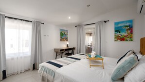 A hotel room with a bed, a desk, and a chair. There are curtains on the windows, and paintings on the walls. - Villa Corinna (Istria - Poreč) (Poreč)