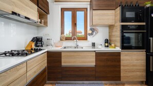 Eine moderne Küche mit Holzausstattung, einem eingebauten Backofen und einem Fenster über der Spüle.