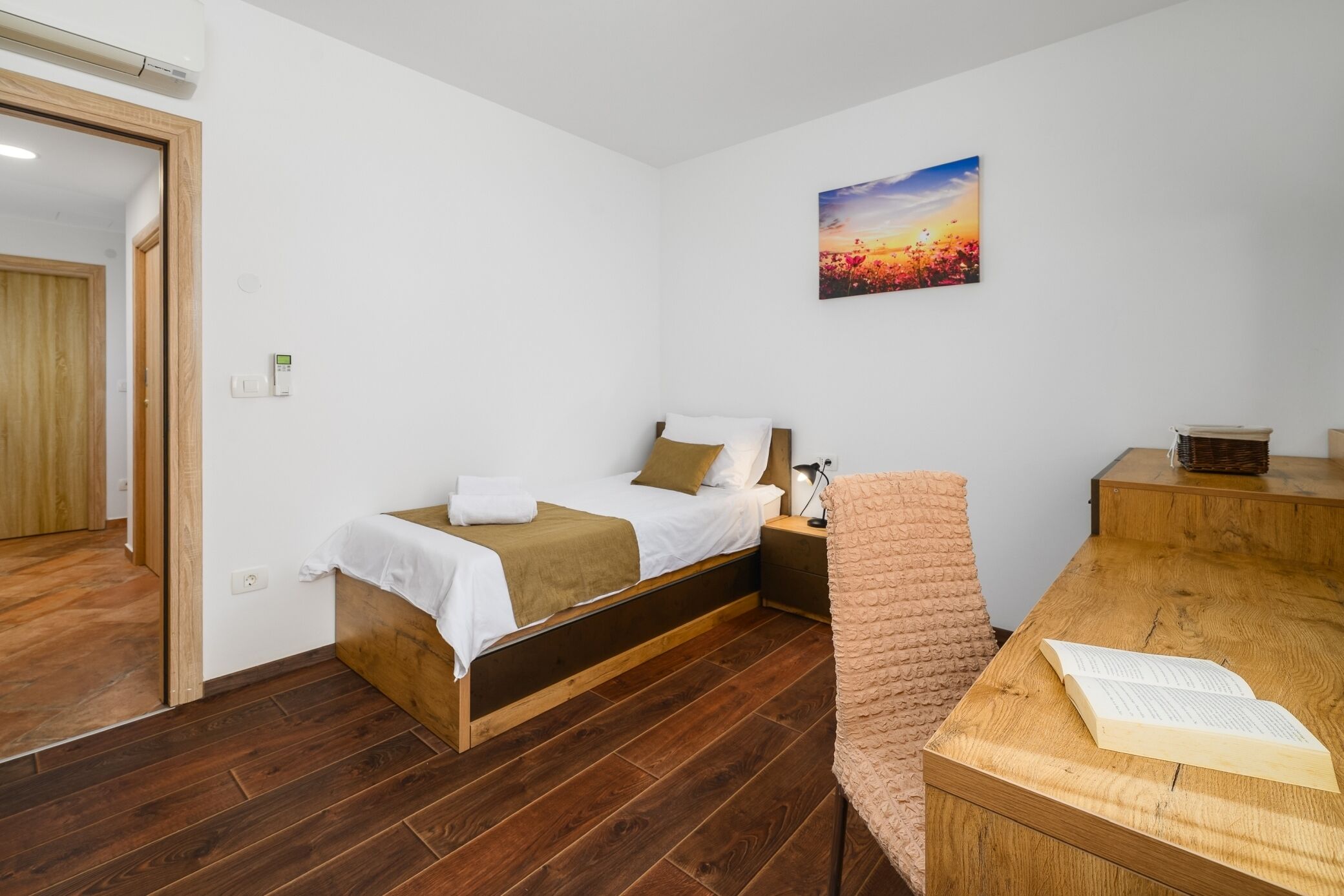 Une chambre à coucher avec un lit, une table de chevet et un bureau sur lequel se trouve un livre.