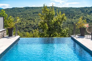 A swimming pool with a view of a forested mountain range.