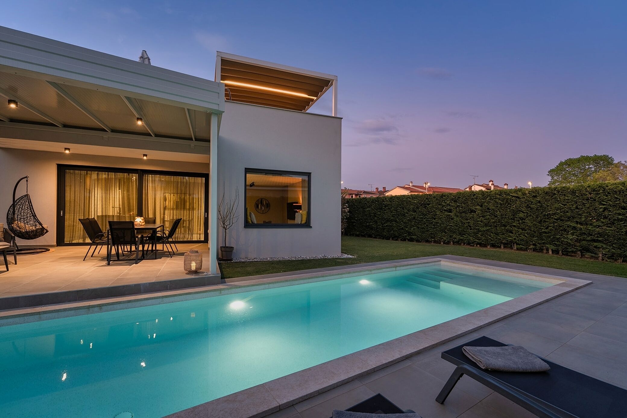 A modern house with a swimming pool, outdoor seating, and a well-maintained garden.
