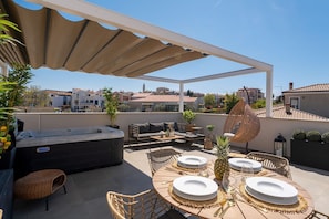 A rooftop patio with outdoor seating, a hot tub, and a view of the cityscape.