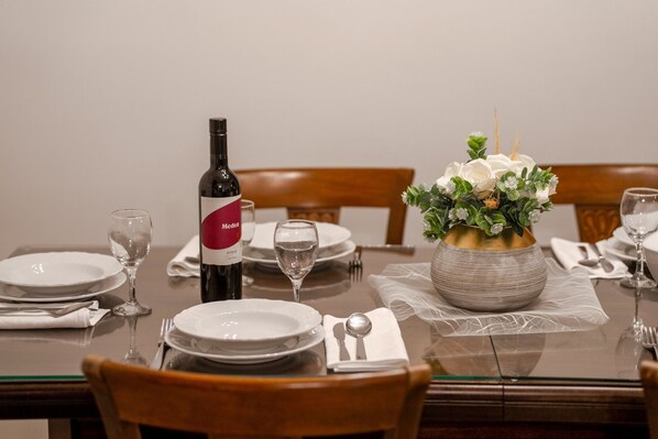 A dining table set with plates, glasses, cutlery, a wine bottle, and a floral centerpiece. - Villa Stauri (Istria - Žminj) (Žminj)