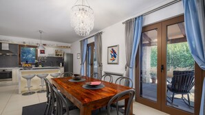 Une cuisine moderne avec une table à manger en bois, des chaises grises et un lustre.