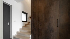 Una escalera moderna con una pared de madera oscura y una puerta blanca.