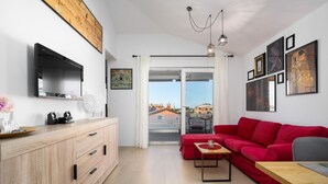 A modern living room with a red sofa, wooden furniture, and artwork on the walls. - Apartment Vanilla Sky (Istria - Poreč) (Poreč)