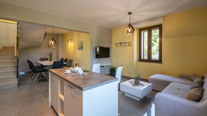 Een moderne keuken met een eethoek, een bank en een televisie.