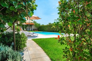 A backyard with a swimming pool, a lounge chair, and a pergola.