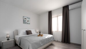 A modern bedroom with a bed, bedside table, and a window with curtains. - Villa Demetra (Istria - Tinjan) (Tinjan)