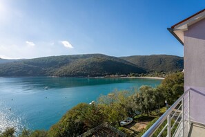 Un balcón con vistas a un lago turquesa, rodeado de vegetación y colinas.