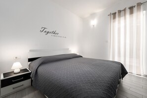 A modern bedroom with a bed, nightstand, and wall-mounted light. - Apartment Astrid 1 (Istria - Labin) (Labin)