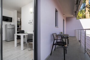 A modern kitchen with a refrigerator, microwave, and a dining area with a table and chairs. - Apartment Astrid 1 (Istria - Labin) (Labin)