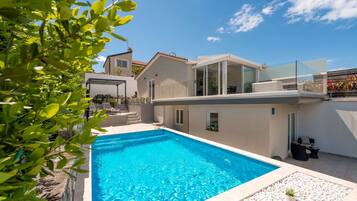 Enjoy a refreshing swim in the pool surrounded by a beautifully maintained garden and patio area.