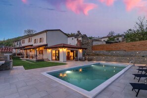 Une maison moderne dotée d’une piscine, d’un espace salon extérieur et d’un mur en pierre.