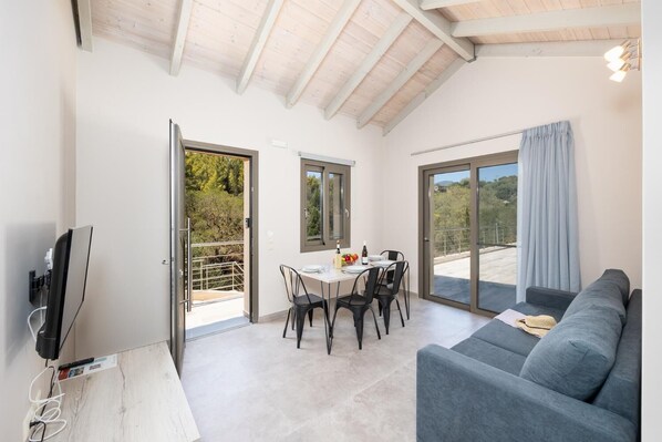 Een ruime woonkamer met balkon, een eettafel met stoelen, een bank en een televisie.