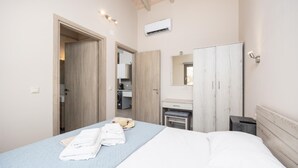 A bedroom with a bed, a wardrobe, a mirror, and a small desk with a chair.