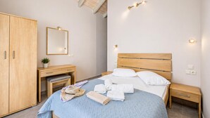 Ein Schlafzimmer mit Bett, Nachttischen, einem Kleiderschrank, einem Schreibtisch mit Stuhl, einem Spiegel und einer Deckenleuchte.