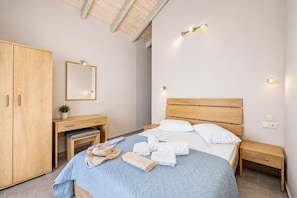 Une chambre à coucher comprenant un lit, des tables de chevet, une armoire, un bureau avec une chaise, un miroir et un luminaire au plafond.