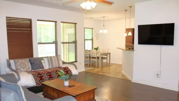 A living room with a sofa, coffee table, and a TV mounted on the wall. - Robert House 3BR + TV all rooms • For Work/Getaway (Robert)