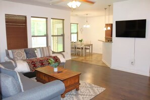 Un salon avec un canapé, une table basse et un téléviseur fixé au mur.