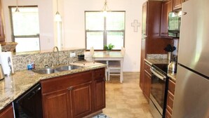 A kitchen with granite countertops, wooden cabinets, a stainless steel refrigerator, and a built-in oven. - Robert House 3BR + TV all rooms • For Work/Getaway (Robert)