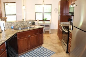 A kitchen with granite countertops, wooden cabinets, a stainless steel refrigerator, and a built-in oven.