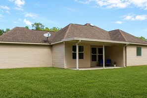 A single-story house with a covered patio, a satellite dish, and a small lawn.