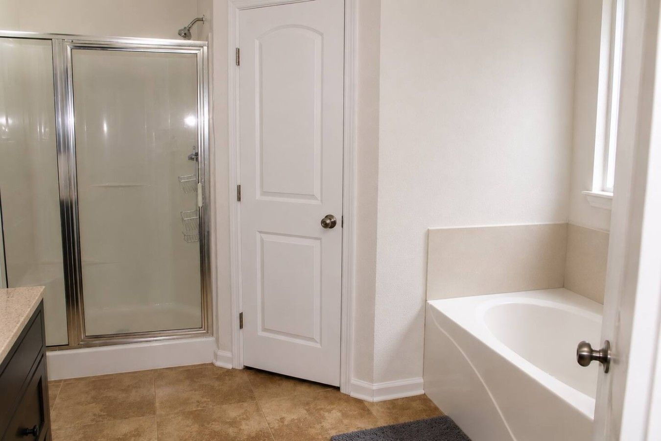 Un baño con cabina de ducha de vidrio, una puerta blanca y una bañera.