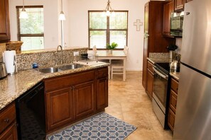 A kitchen with granite countertops, wooden cabinets, a stainless steel refrigerator, and a built-in oven.